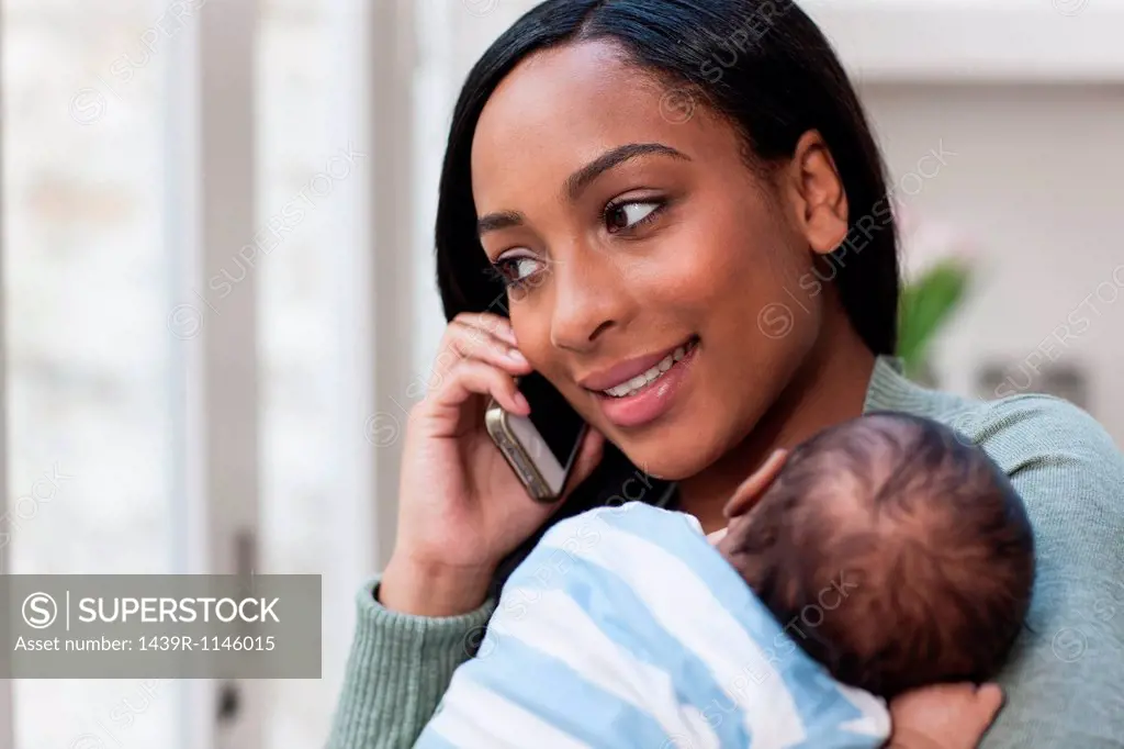 Mother on cellphone, holding baby son