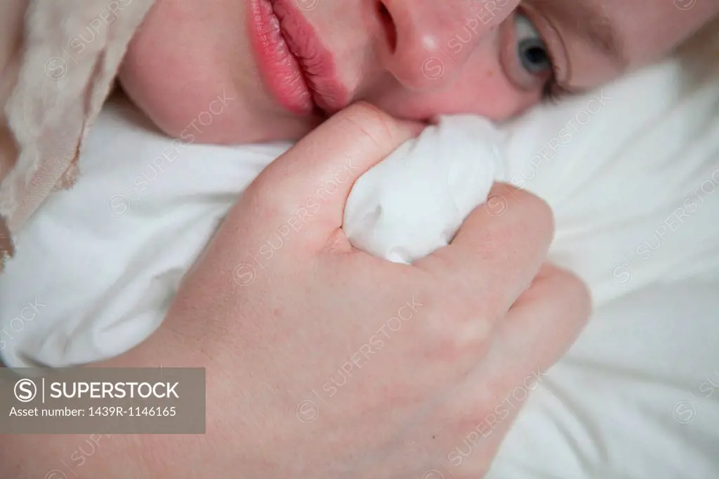 Young woman gripping bed sheet