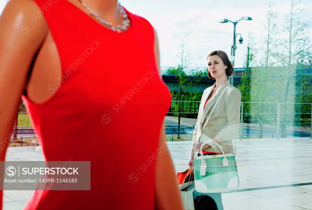 Woman looking at dress on mannequin in shop window