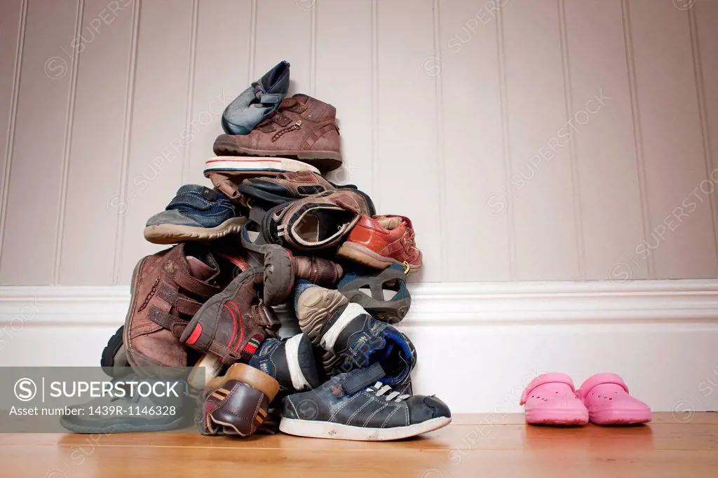 Large pile of boy´s shoes beside one pair of girl´s shoes