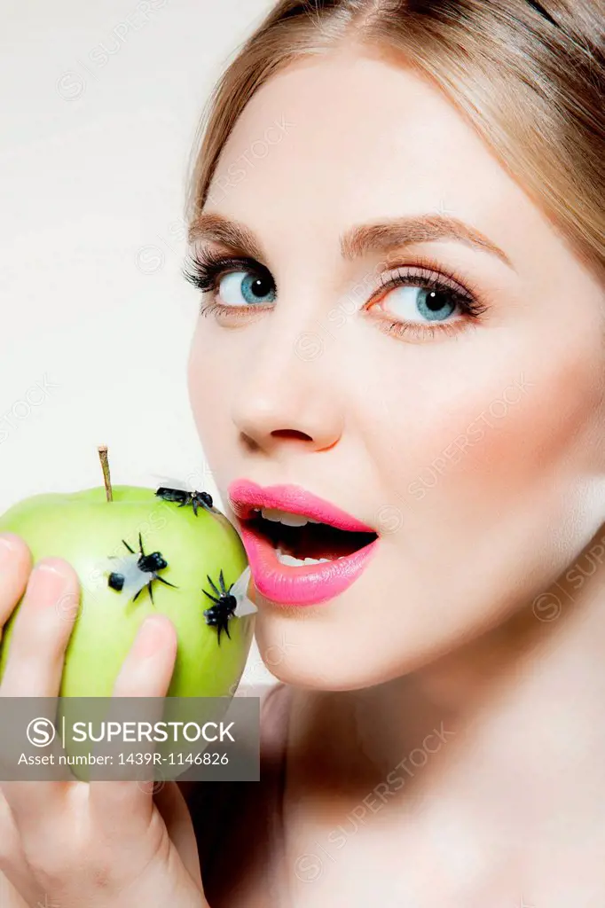 Young woman eating apple with flies on it