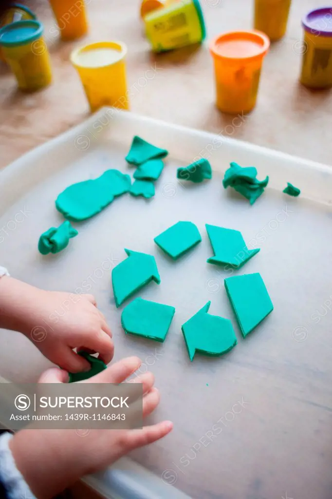 Child making recycling symbol from play clay