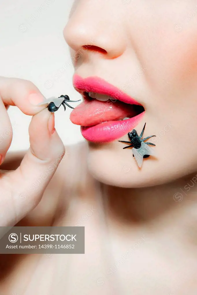 Young woman with plastic fly on tongue