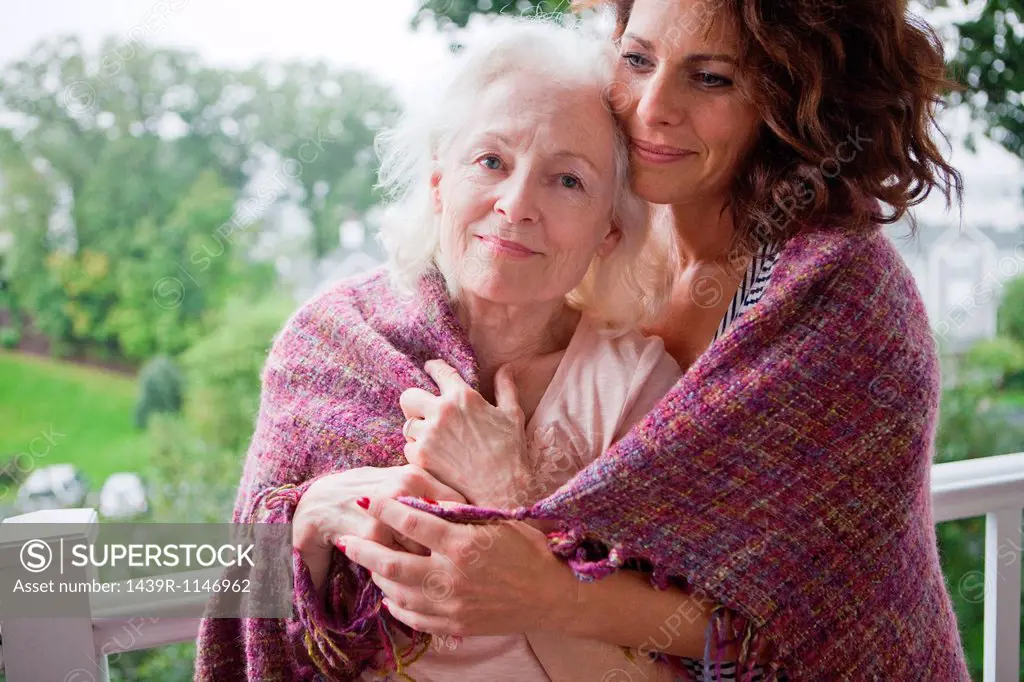 Senior woman and daughter embracing on porch, portrait