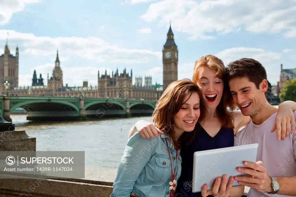 Friends looking at a digital tablet together in London