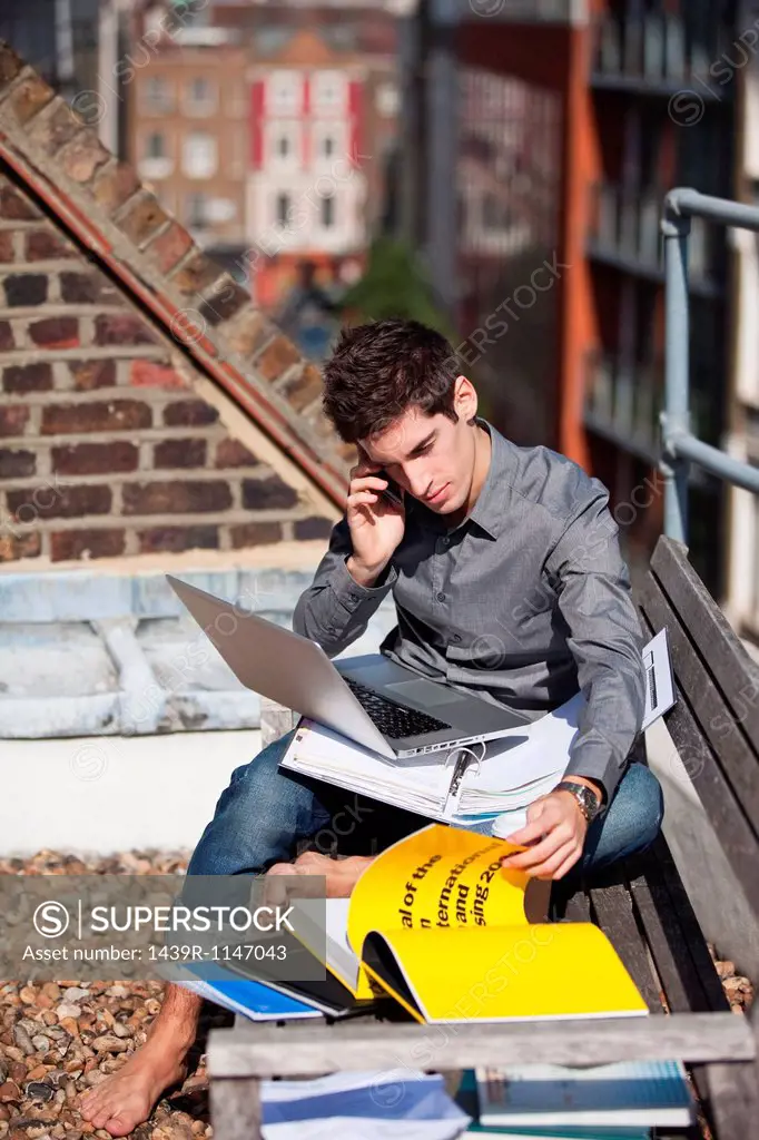 Young man working with a laptop on a rooftop