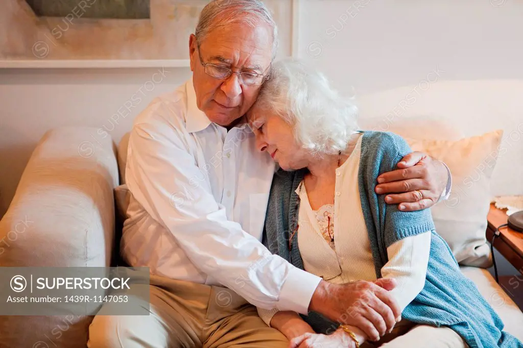 Senior couple embracing on sofa at home