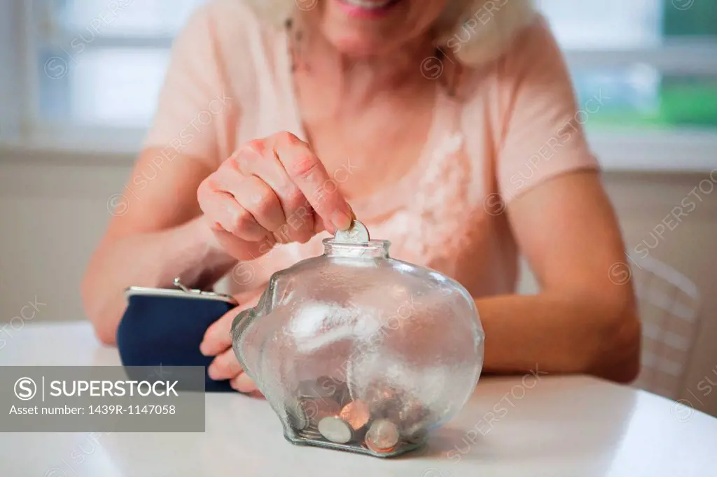 Senior woman saving money in piggy bank