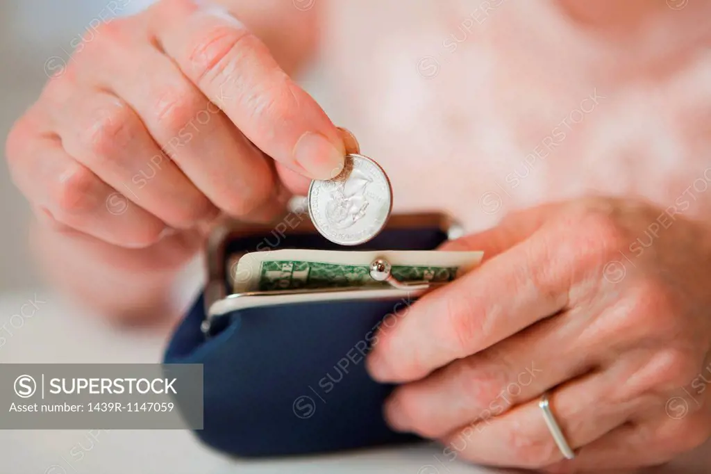 Senior woman saving money in purse
