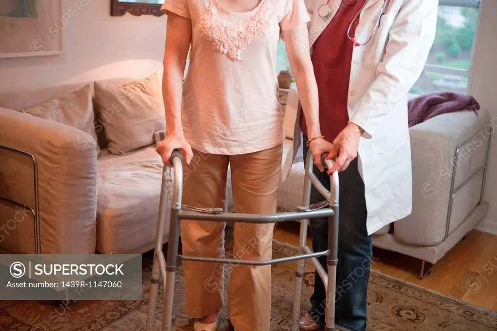 Doctor supporting senior woman on walking frame
