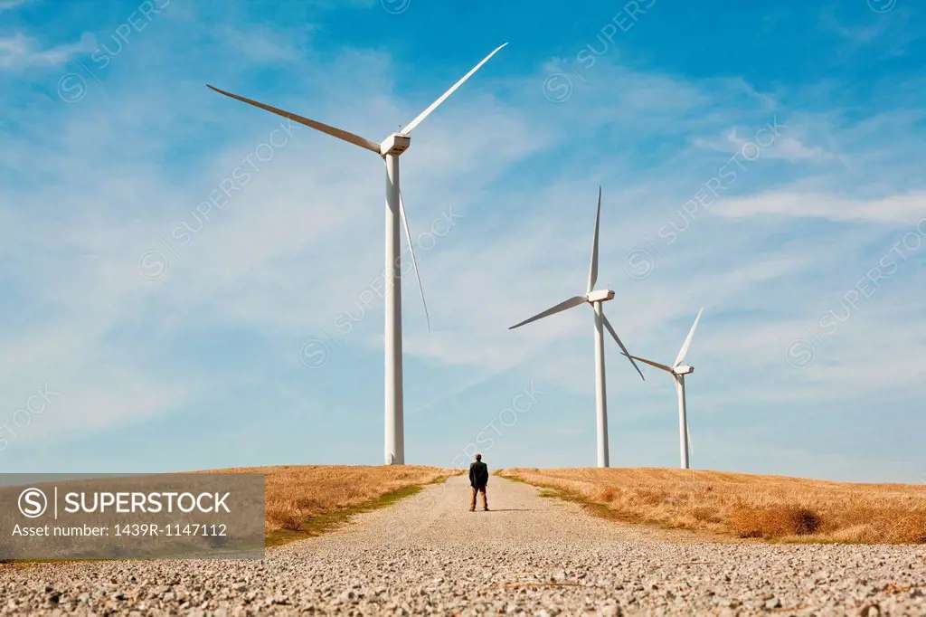 Distant view of man in front of wind turbines
