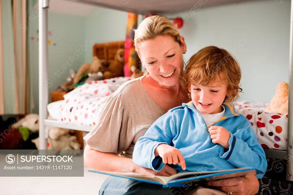 Mother reading a book with her son in his bedroom