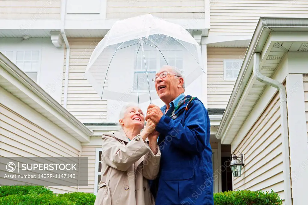 Senior couple holding umbrella outside