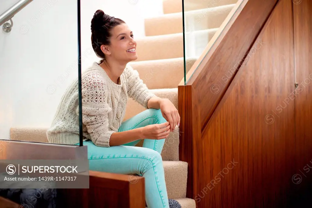 Young woman sitting on stairs, smiling