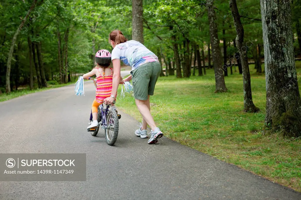 Mother helping daughter to ride bicycle