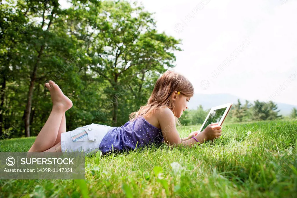 Girl lying on grass with digital tablet