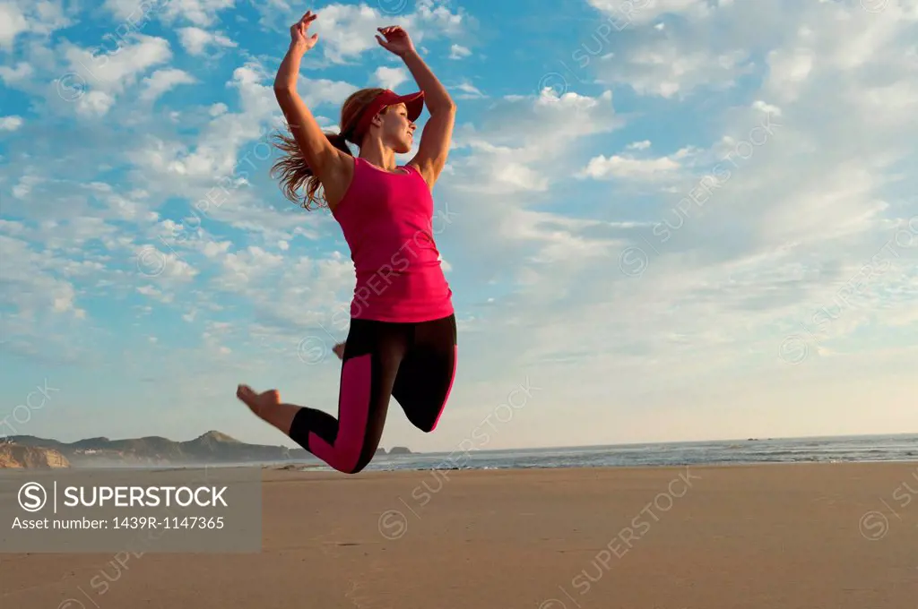 Young woman jumping in the air on beach