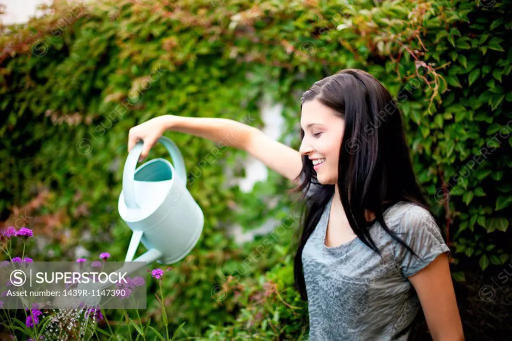 Young woman watering flowers in garden