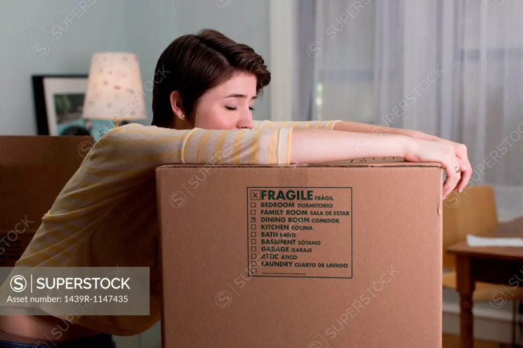 Tired young woman resting on moving box