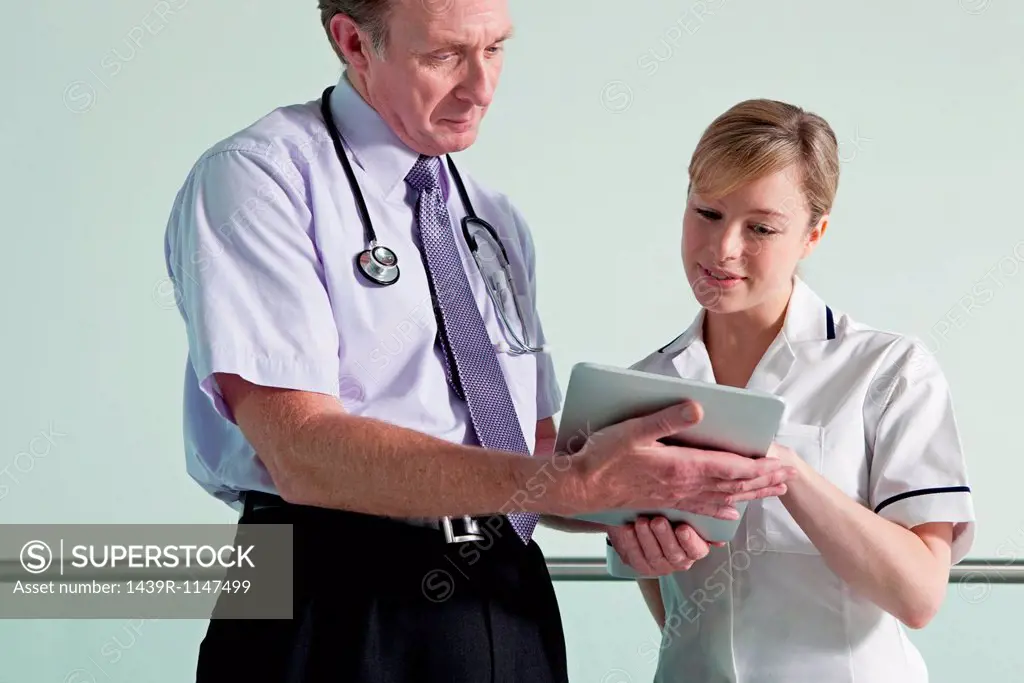 Doctor and nurse discussing medical records on digital tablet