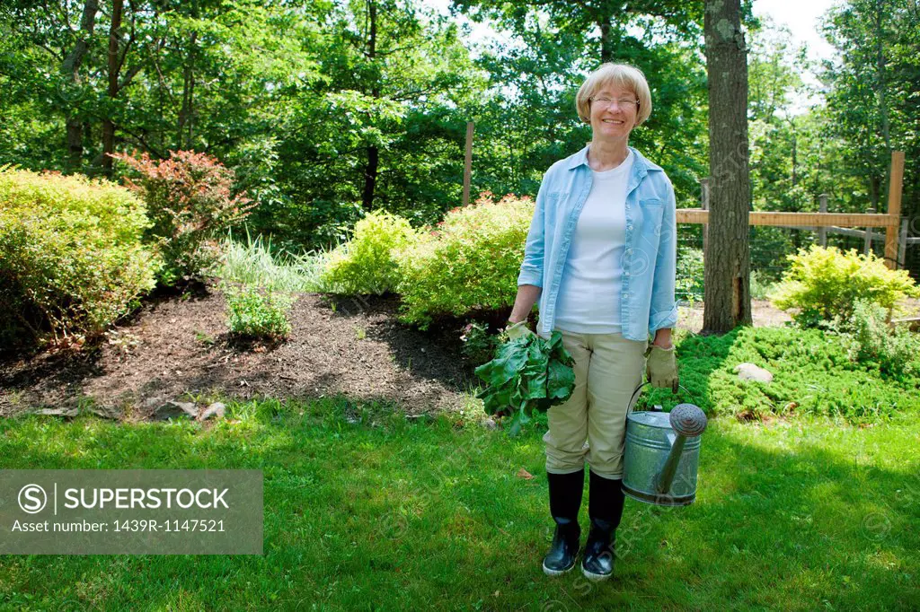 Woman with watering can and beetroot in garden