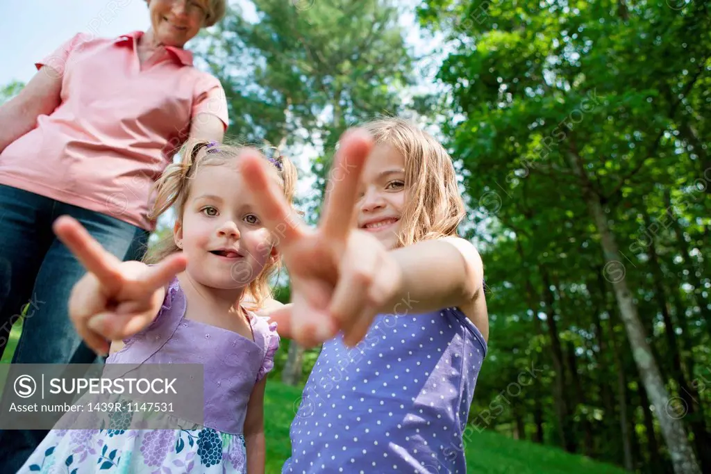 Girls making victory sign with grandmother in background