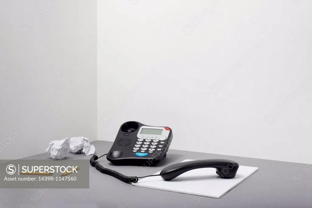 Landline office phone off the hook with pencil and paper