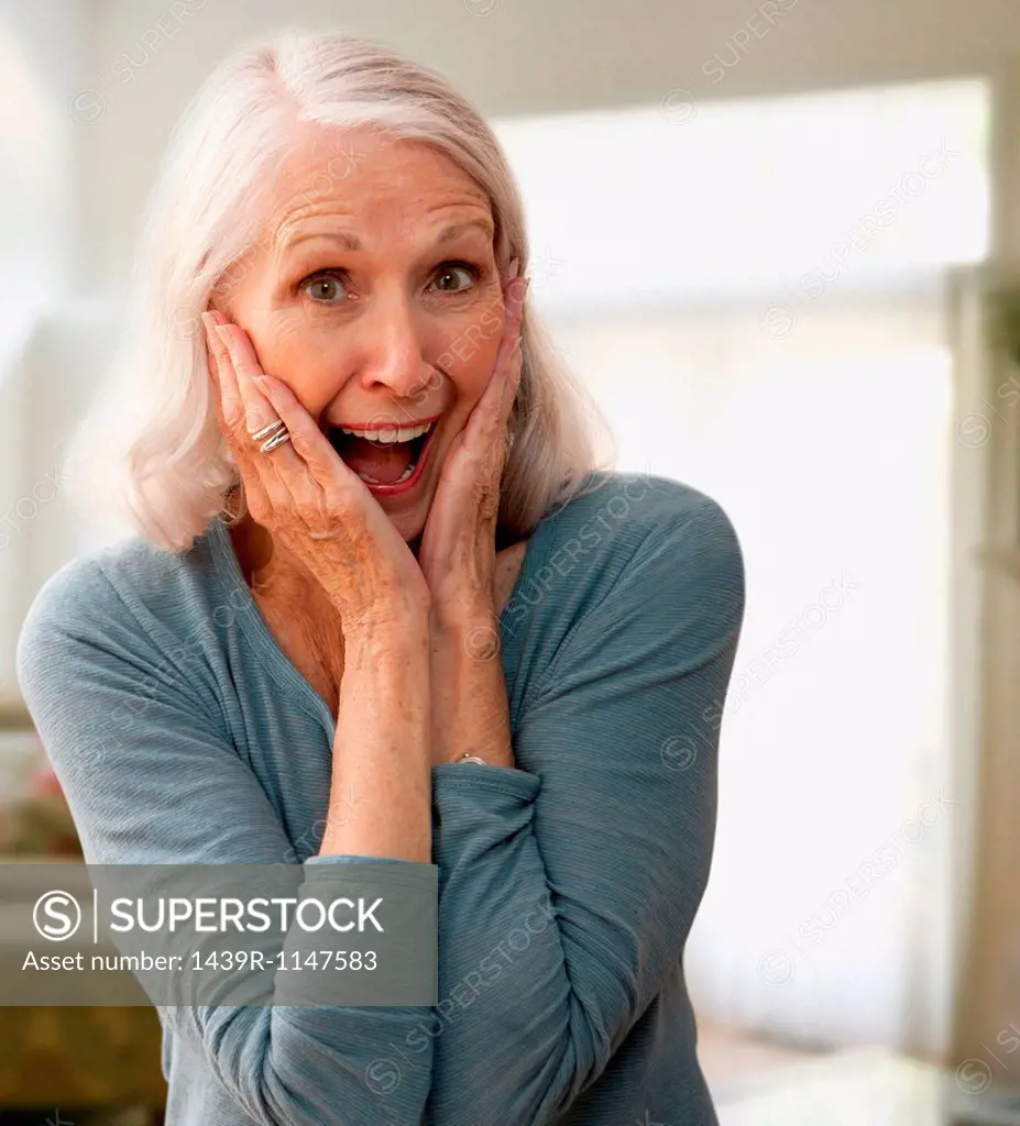 Senior woman gasping with mouth open, touching face