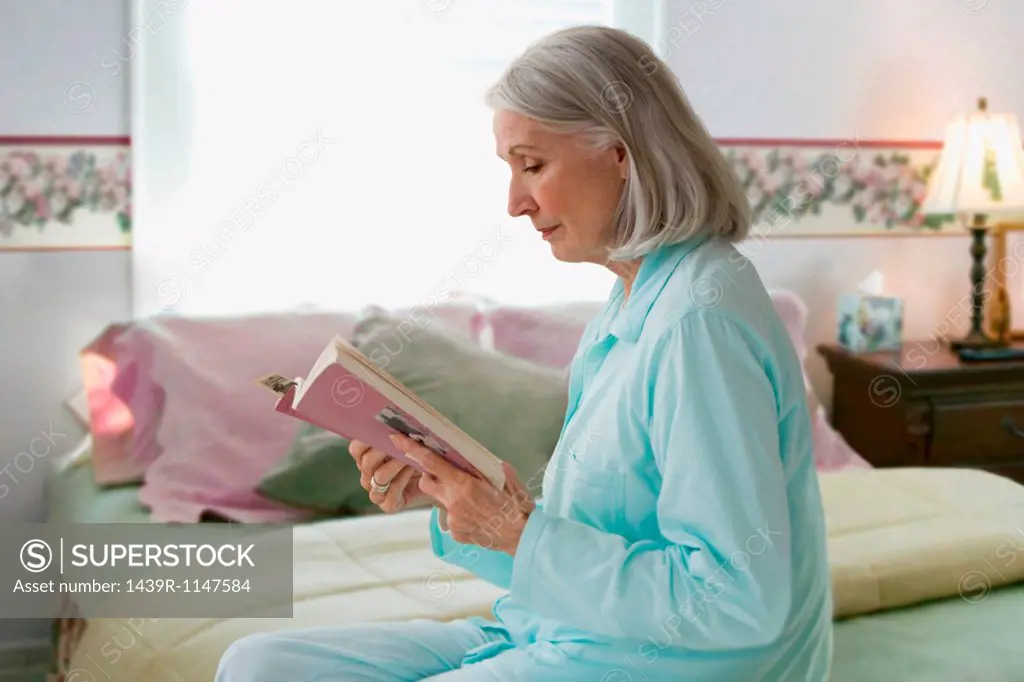 Senior woman reading book in bedroom