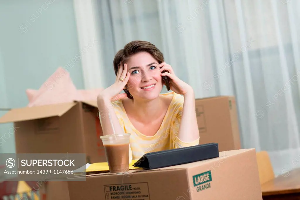 Young woman on cellphone whilst moving house