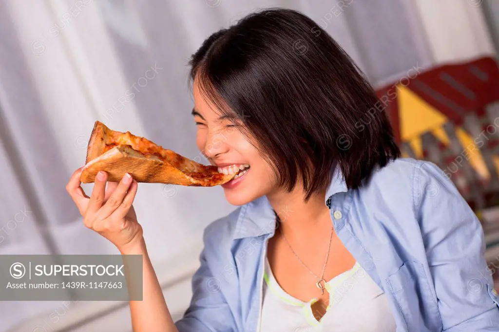 Young woman biting a slice of pizza