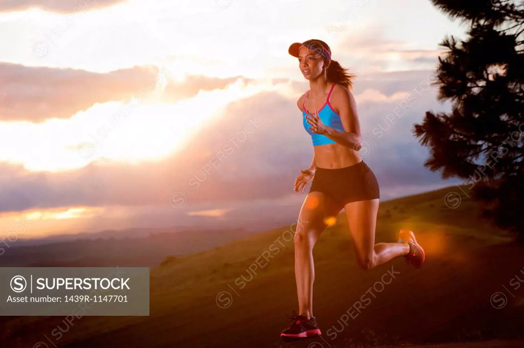 Young woman running in rural setting at sunrise