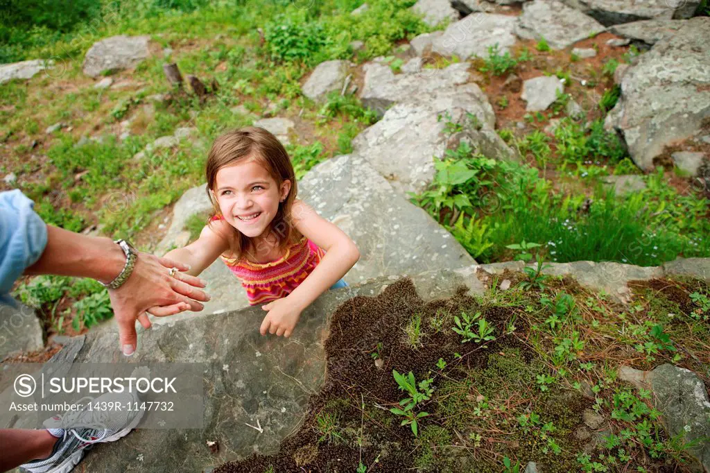 Mother helping daughter climb rocks
