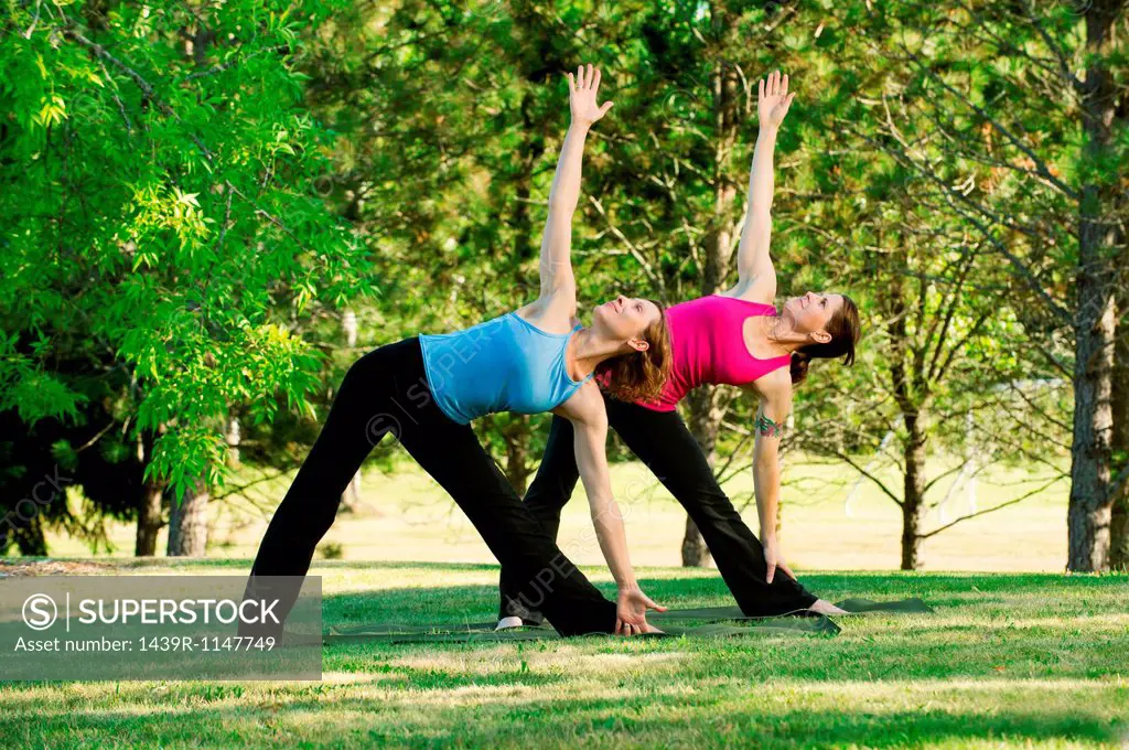 Two women practising yoga together in a park