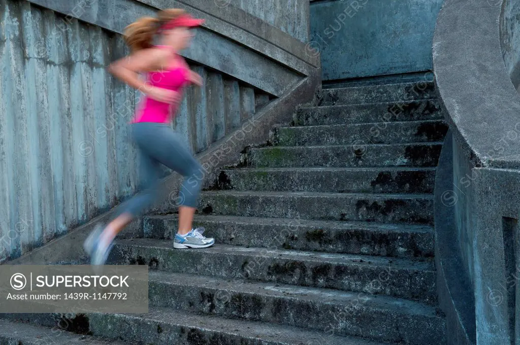 Young woman running up stairs, motion blur