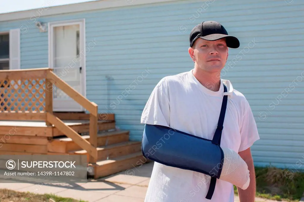 Man outside house with arm in sling