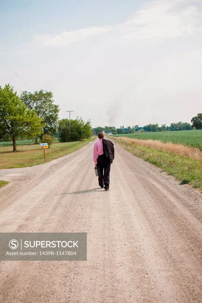 Businessman walking away down a dirt road