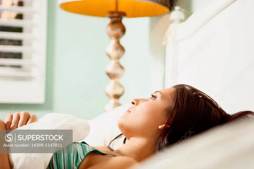 Young woman in bed daydreaming