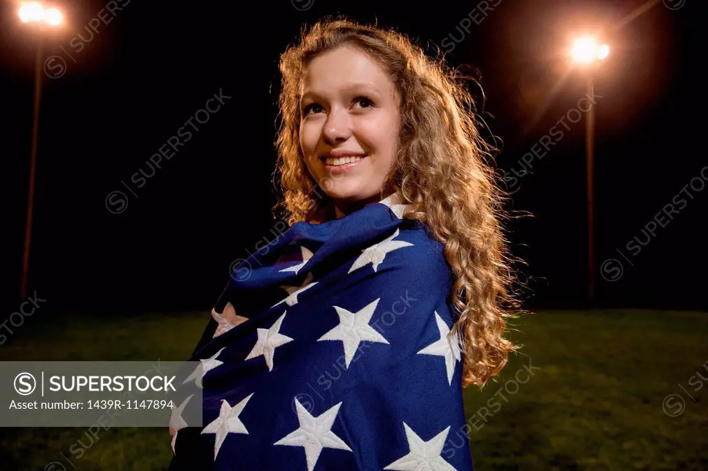 Girl wrapped in american flag at night