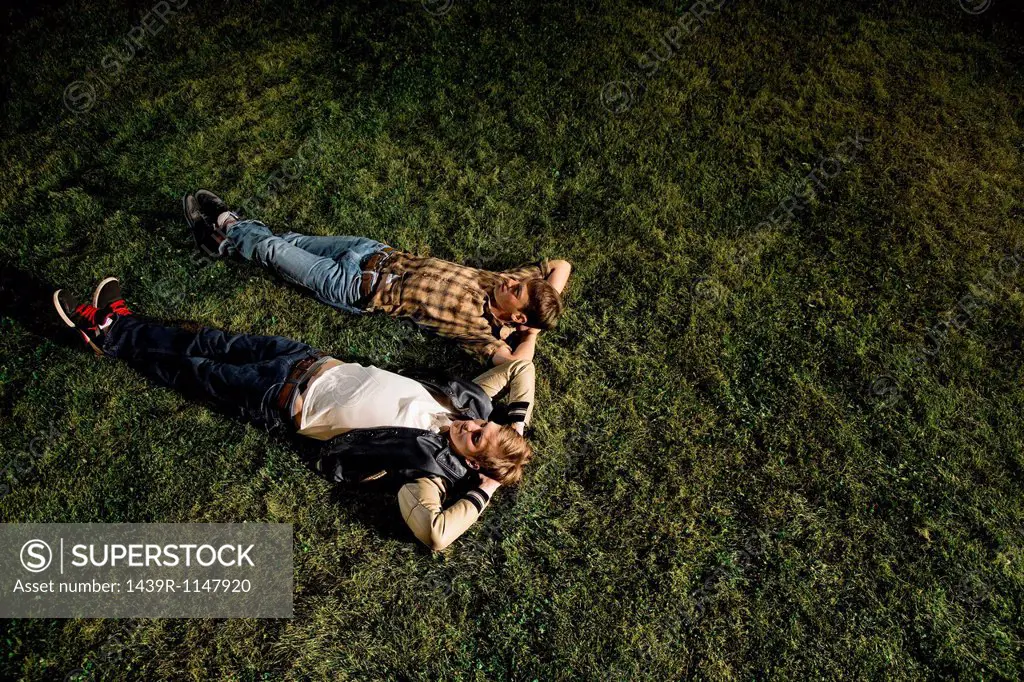 Two young men lying on grass at night, high angle