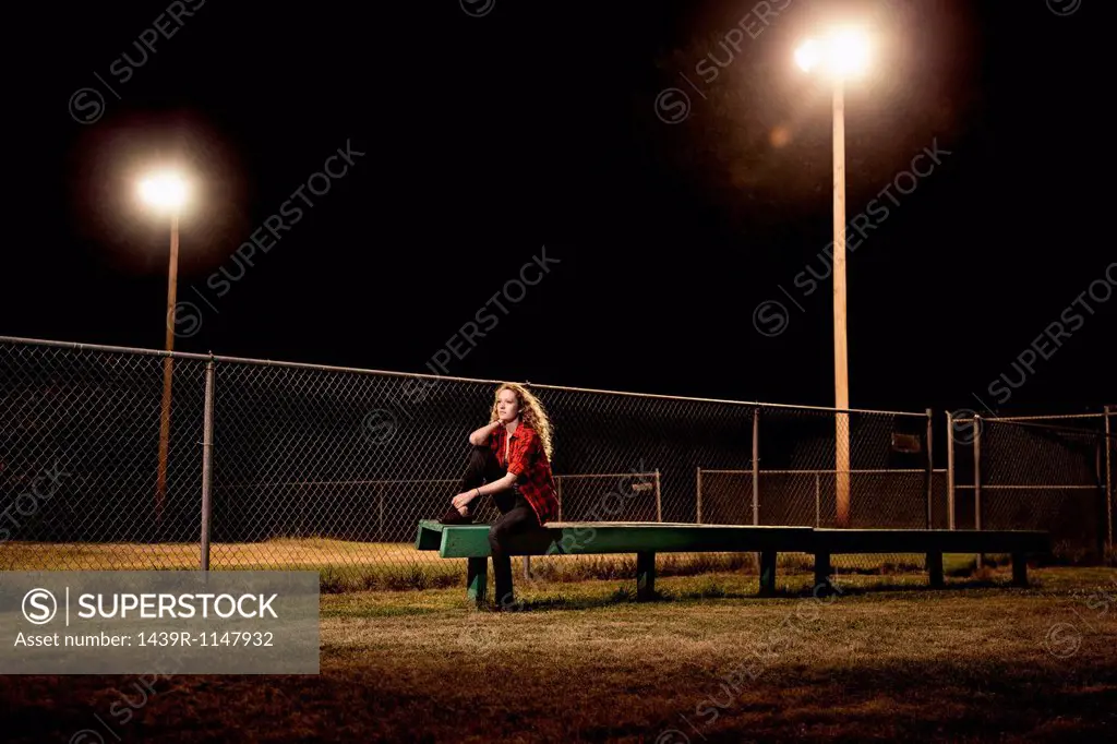 Pensive teenage girl sitting on bleachers at night