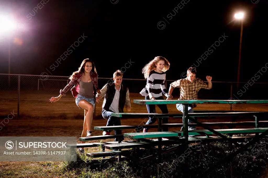 Four friends walking over bleachers at night