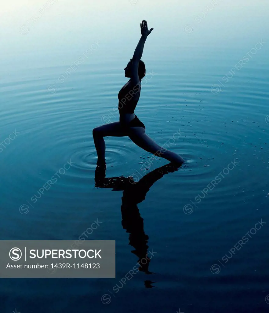 Woman in yoga pose in lake