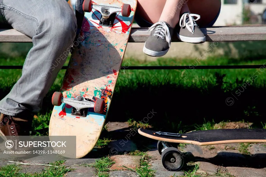 Young couple on bench with skateboards, low section