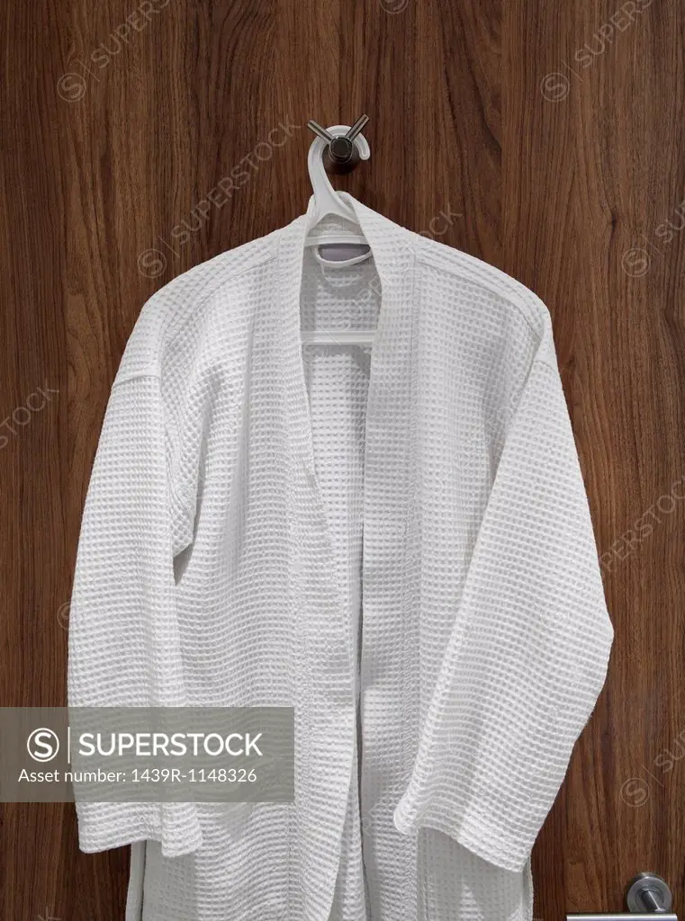 White bathrobe hanging on door