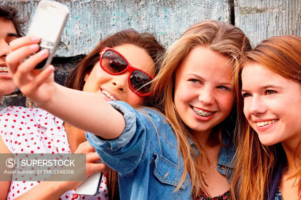 Teenage girls taking a picture of themselves on smartphone