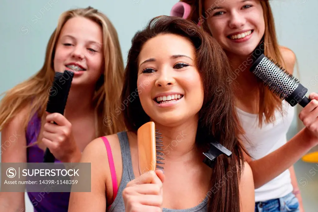 Teenage girls singing into hairbrushes
