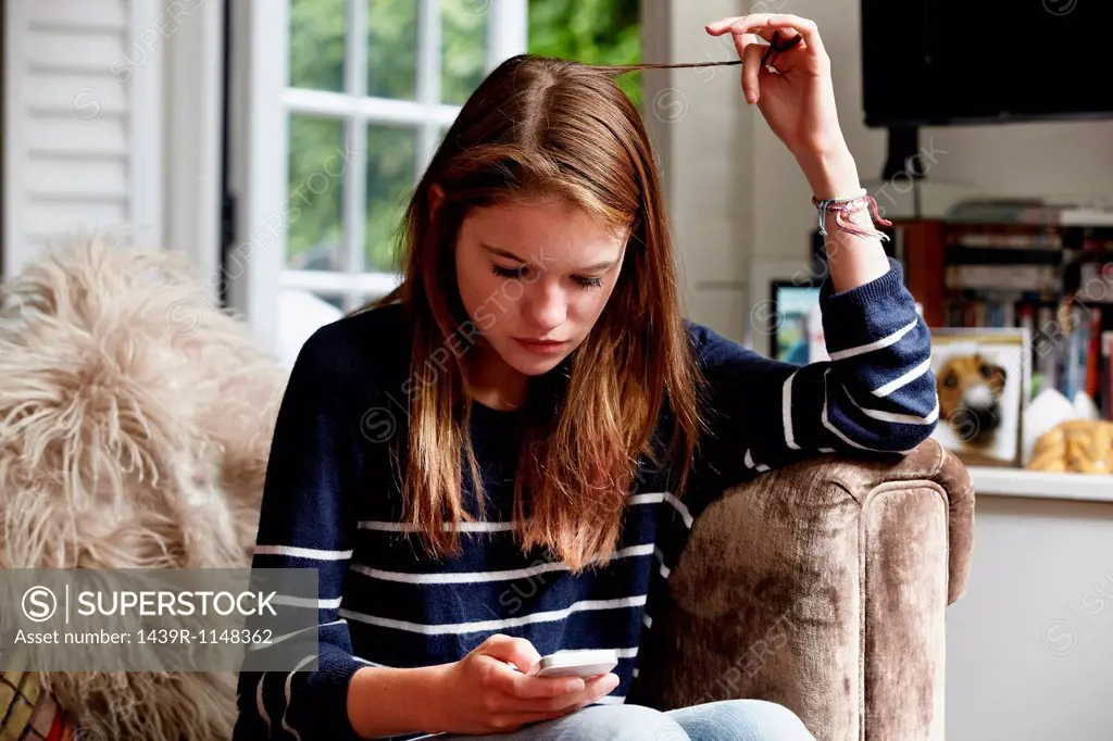 Teenage looking at cellphone and playing with her hair