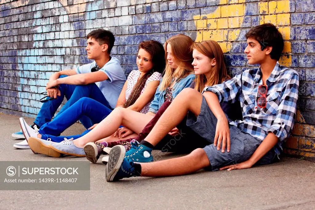 Teenagers sitting against a wall