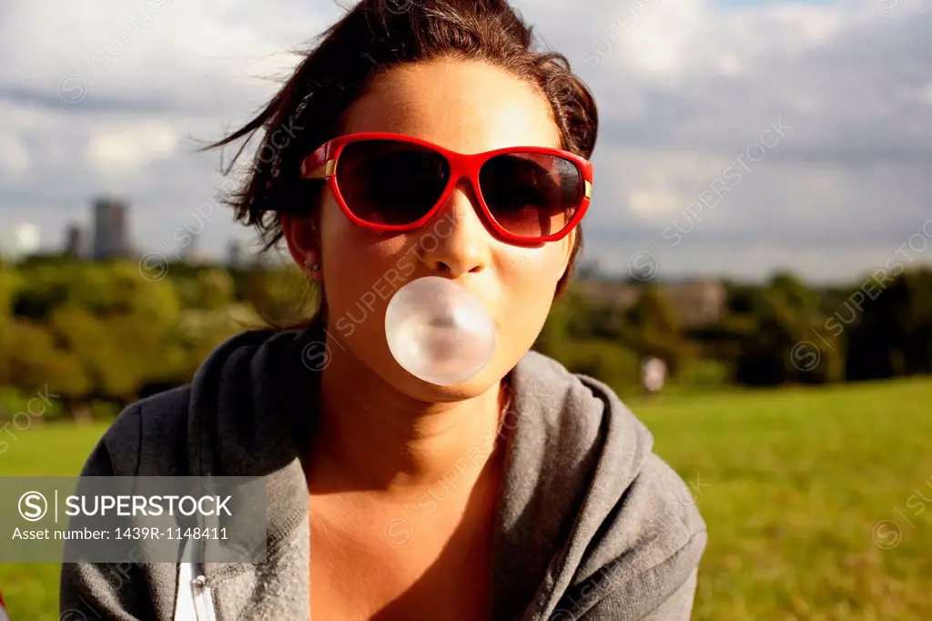 Teenage girl in sunglasses, blowing bubble gum